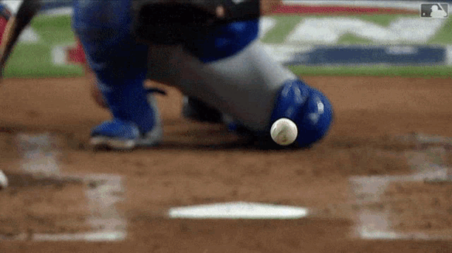 a baseball is being thrown at a base while a catcher looks on