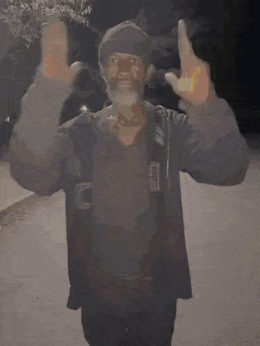 a man with a beard is standing with his hands folded in front of him .
