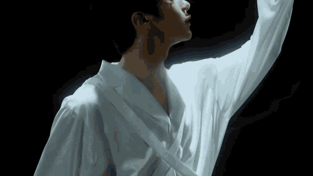 a man in a white shirt is standing with his arm outstretched