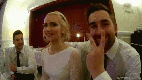 a man is giving a peace sign while a woman looks on