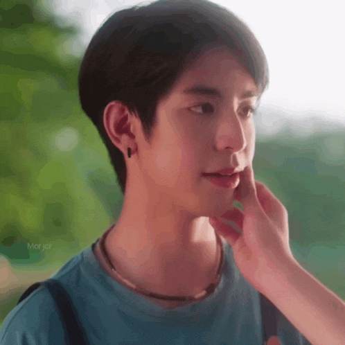 a person is touching a young man 's face with their hand .