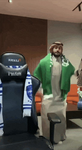 a man with a scarf around his neck is standing in front of a gaming chair that says i16n2m