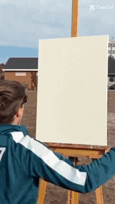 a person is standing in front of an easel holding a canvas .