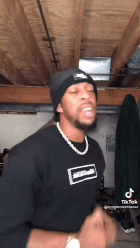 a man wearing a beanie and a necklace is dancing .