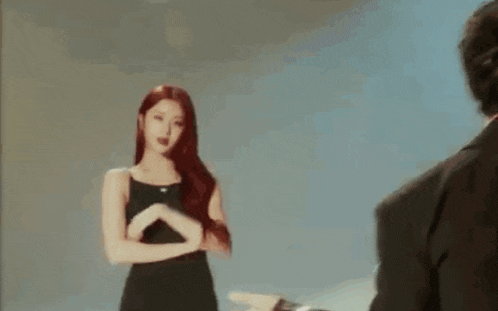 a woman in a black dress is standing next to a man in a suit and looking at him .