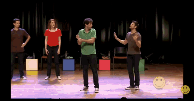 a group of people are standing on a stage with a smiley face in the corner