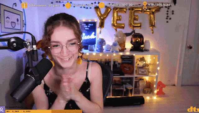 a woman sitting in front of a microphone with the word yeet balloons behind her