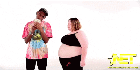 a man in a tie dye shirt stands next to a woman in a bra