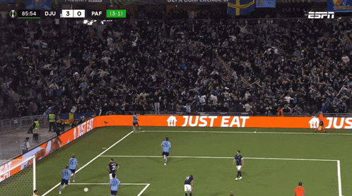 a soccer game is being played in front of a large crowd and a sign that says just eat