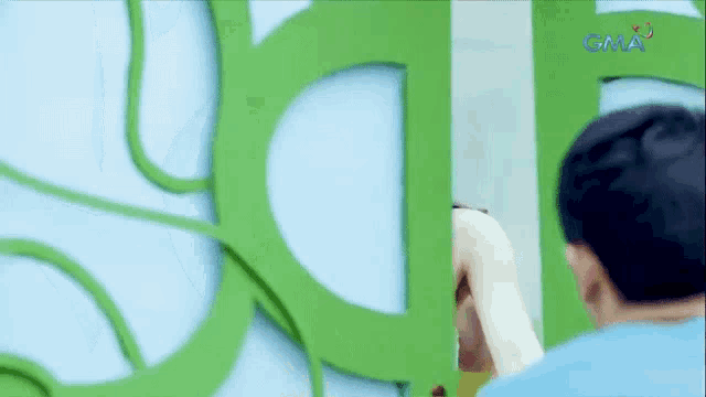 a man is standing in front of a green sign that says gma