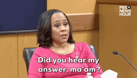 a woman in a pink dress is sitting in front of a microphone and saying did you hear my answer ma 'am
