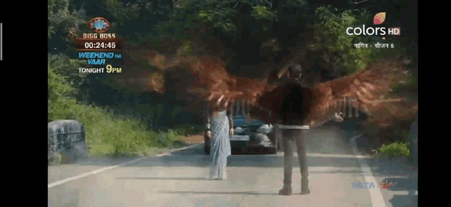 a man and a woman are standing on a road in front of a car and a sign that says big boss