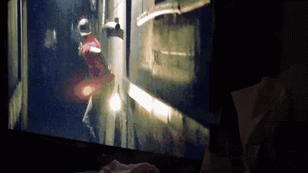 a man in a red shirt is walking down a dark hallway on a screen
