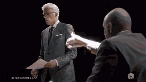 a man in a suit is standing in front of a wooden door holding a piece of paper .