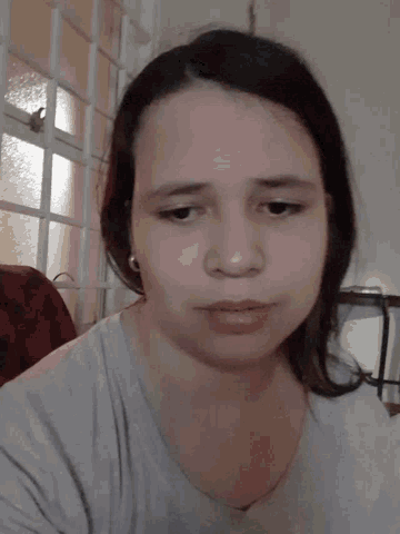 a close up of a person 's face with a gray shirt on