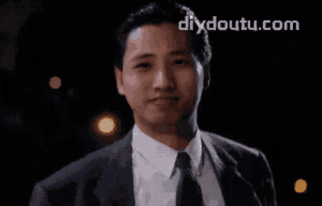 a man in a suit and tie is smiling and the website diydoutu.com is visible behind him