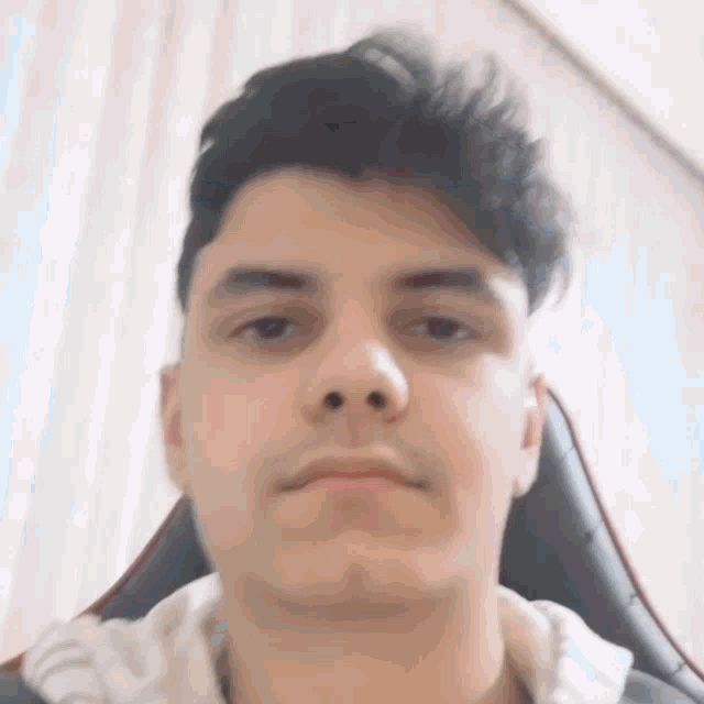 a close up of a man 's face while sitting in a chair looking at the camera .