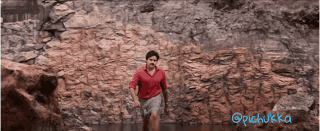 a man in a red shirt is running through a rocky area with the name pichukka written below him
