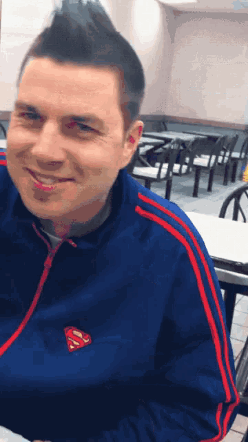 a man wearing a blue jacket with a superman logo on the front