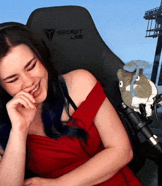a woman in a red dress is sitting in a black secret lab chair