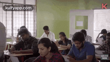 a group of students are sitting at their desks in a classroom taking a test .