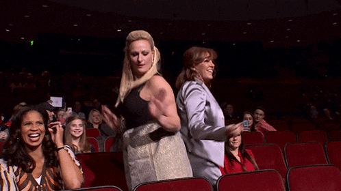 two women are dancing in a theater with a sign that says exit on it
