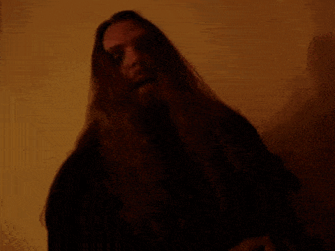 a man with long hair and a beard is sticking out his tongue