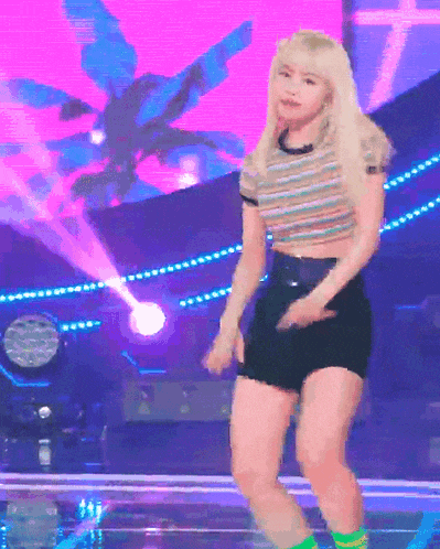 a woman is dancing on a stage with a purple background