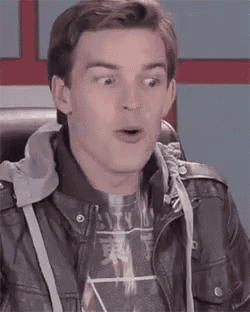 a young man in a leather jacket and a hoodie is making a surprised face .