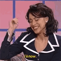 a woman in a suit is smiling and saying " i know "