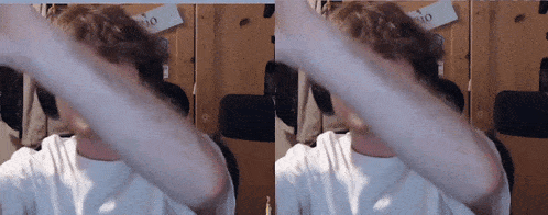 a man in a white shirt covering his face with his arms