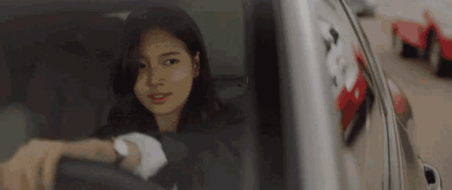 a woman is sitting in the driver 's seat of a car looking out the window .