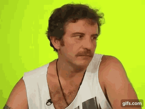 a man with a mustache is wearing a tank top and a microphone .