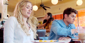 a man and a woman are sitting at a table in a diner eating food