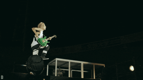 a person playing a green guitar on a stage with a sign that says d