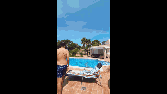 a shirtless man stands in front of a pool