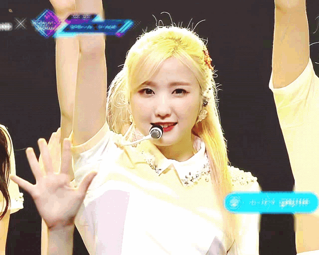 a girl with blonde hair and a microphone on a stage