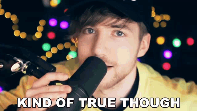 a man singing into a microphone with the words " kind of true though " above him