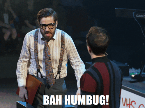a man with suspenders and a beard stands next to another man with the words bah humbug written on his pants
