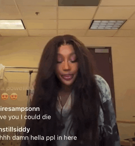a woman with long hair is making a funny face in a room with other people