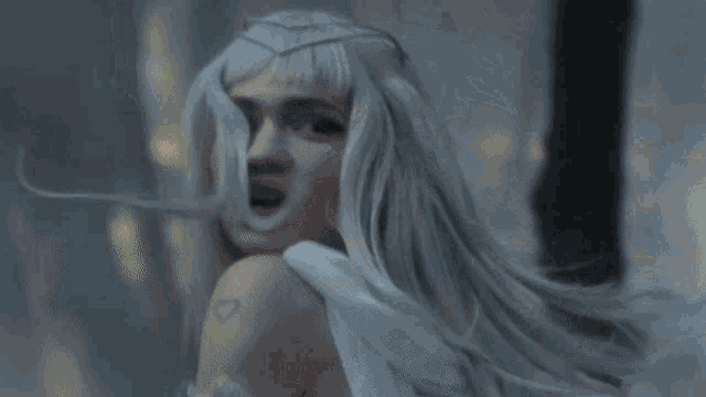 a woman with long white hair is wearing a white dress and a white wig .