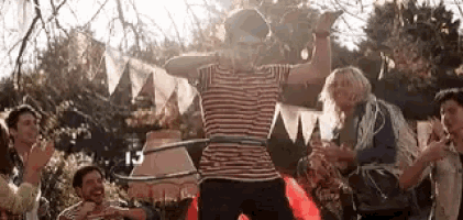 a man is playing with a hula hoop while a group of people applaud .