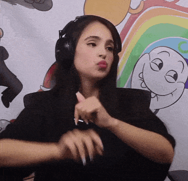 a woman wearing headphones making a funny face in front of a cartoon wall