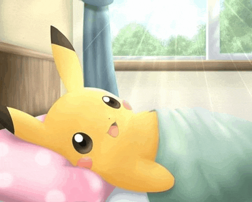 a pikachu is laying on a bed with a pink pillow and blanket .