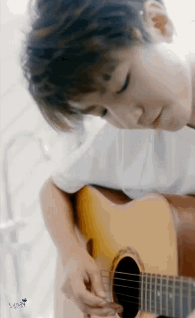 a close up of a person playing an acoustic guitar with their eyes closed
