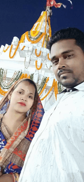 a man and a woman pose for a picture in front of a decorated temple