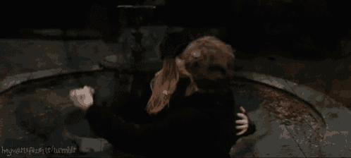 a man and a woman are hugging each other in front of a fountain in a dark room .