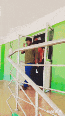 a man in a green shirt is walking down a set of stairs next to a green wall