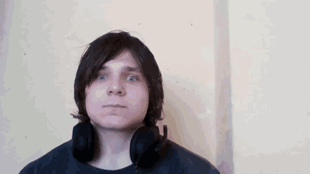 a young man wearing headphones looks at the camera .