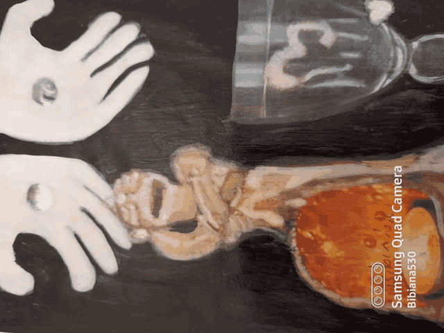 a samsung quad camera shows a painting of two hands and a glass